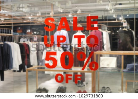 A sign of sale up to 50% off mock up advertise display frame setting over clothes fashion store in shopping mall, Shopping and discount in department store concept.