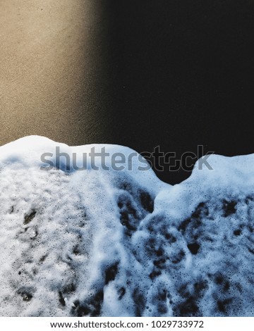 Sea foam on the beach half in shadow close-up