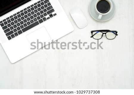top view of wooden table top with computer laptop , mouse, coffee, and eye glasses Royalty-Free Stock Photo #1029737308