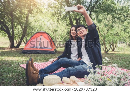 happy couple camping on the nature, taking a selfie shot of smiling with smartphone, camping, travel, tourism, hiking and people concept.