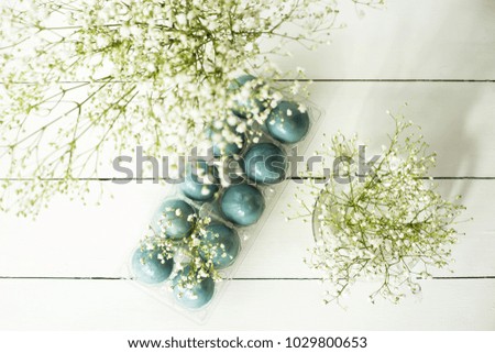 Blue easter eggs on a white table among bouquets of gypsophila