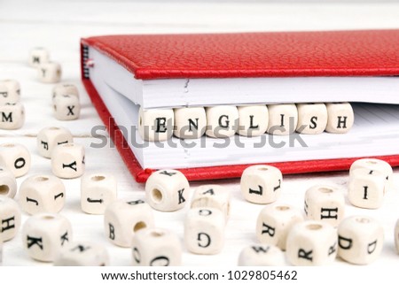 Word English written in wooden blocks in red notebook on white wooden table. Wooden abc.