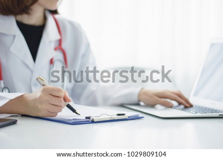 Female doctor writing medical prescription or certificate