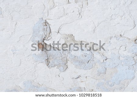 Uneven surface. White peeling paint. Many small cracks.