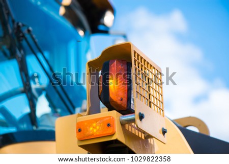 Yellow warning lights on excavator. Road construction workers repairing highway road on sunny summer day. Loaders and trucks on newly made asphalt. Heavy machinery working on street