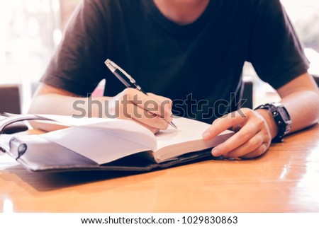 Close up of young hand writing notes in study room. Royalty-Free Stock Photo #1029830863