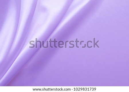 Smooth elegant wavy purple / violet pastel color silk or satin luxury cloth fabric texture, abstract background design.