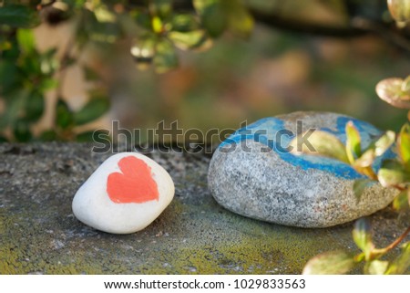 Heart painted with a red paint on the pebble as a gift for Saint Valentine's day on the pebble background. Copy space for text