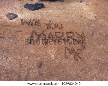 Will you marry me hand written in sand on a beach