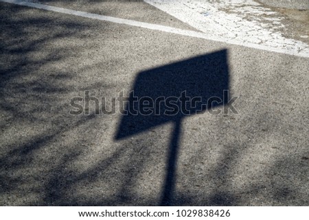 Shadow street sign on asphalt road, urban background.