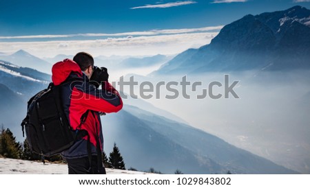 Man photographing the alpine landscape at dawn on the snow in the high mountains.