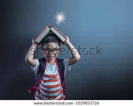 Back to school.Portrait of little Asian child boy thinking and put a book on top with copy space.Lightbulb picture on a book.