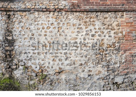 Panoramic image of Decorativeold flint, red brick, wall with green and yellow vegetable moss