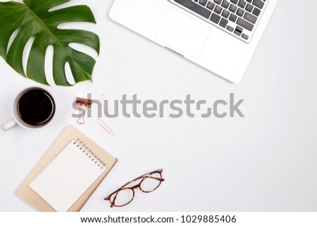 Woman home office desk workspace with laptop, tropical palm leaf, glasses, notebook and coffee cup on white background. Flat lay, top view. stylish female concept.