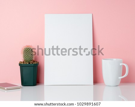 Blank white frame and plant cactus, cup of coffee or tea on a white table against the pink wall with copy space. Mockup with copy space.