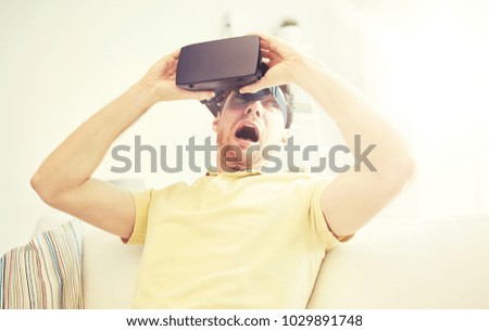 3d technology, virtual reality, gaming, entertainment and people concept - scared young man taking off virtual reality headset or 3d glasses while playing game