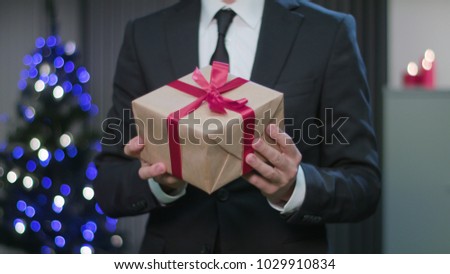 Closeup of a man's hands holding and fumbling a Christmas gift or present. A happy husband concept. Soft focus