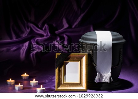 black cemetery urn with golden mourning frame and white tape