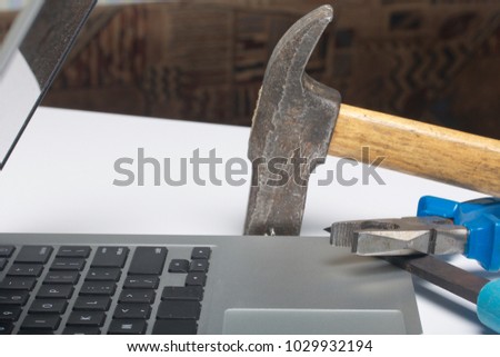 Laptop and work tools. On the white surface of the table is a tablet, skein, chisel and pliers. Destruction and repair of electronic devices.