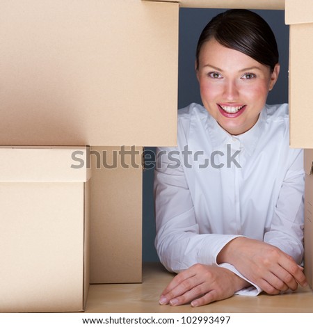 Portrait of young woman surrounded by lots of boxes. Lots of work concept.