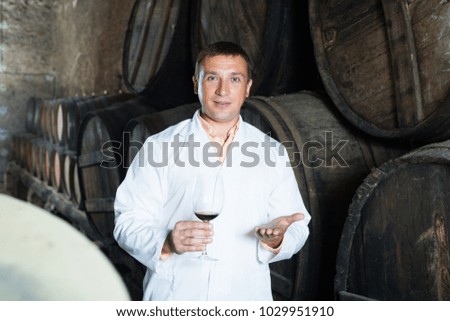 Glad young male in robe keeping ageing process of wine under control