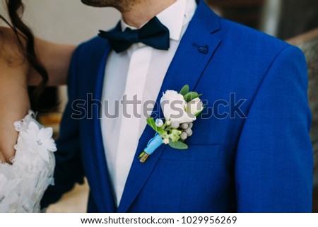 Close-up image of a groom in a blue tuxedo with White boutonniere. Boutonniere on the groom's jacket. Artwork. Selective focus on the flower