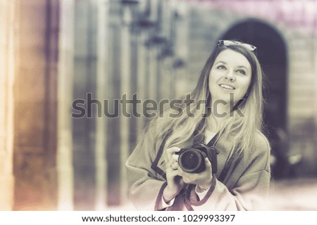 Young happy cheerful woman with a camera looking curious and taking the pictures outdoors