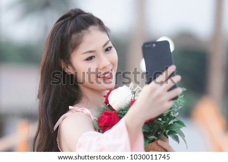 beautiful young woman asian girl standing holding roses red and white smiling zelfie on the bridge in the evening