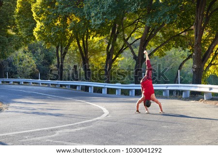 Fit man in red costume doing yoga on the asphalt road in Almaty, Kazakhstan
