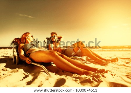 Two lovers on beach and summer time sunset of golden color. 