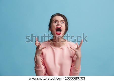 Screaming, hate, rage. Crying emotional angry woman screaming on blue studio background. Emotional, young face. Female half-length portrait. Human emotions, facial expression concept. Trendy colors Royalty-Free Stock Photo #1030089703