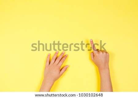 Children hands pointing on yellow background Royalty-Free Stock Photo #1030102648