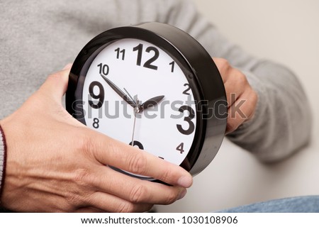 closeup of a young caucasian man adjusting the time of a clock Royalty-Free Stock Photo #1030108906