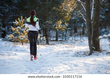 Picture from back of young athlete walking through winter forest