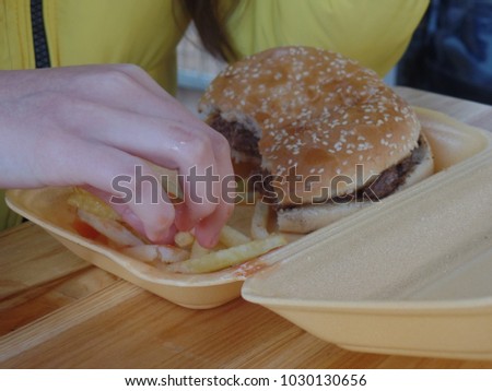 Girl eating a burger and chips out of a container