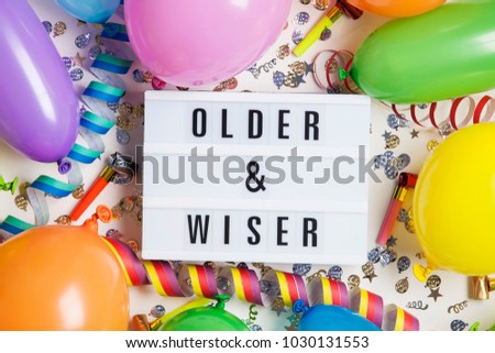 Party celebration background with older and wiser message on a lightbox