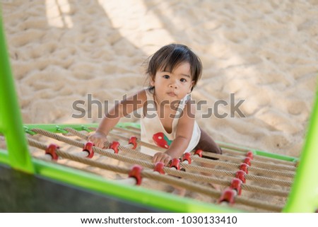 Baby is enjoying rope climbing on the playground.