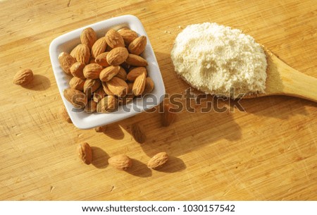 Almond flour in a wooden spoon on a background of nuts almonds. 