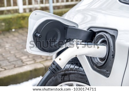 View of an Electric Car Charging and in the background a blurred view of a car Royalty-Free Stock Photo #1030174711