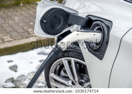 View of an Electric Car Charging and in the background a blurred view of a car Royalty-Free Stock Photo #1030174714
