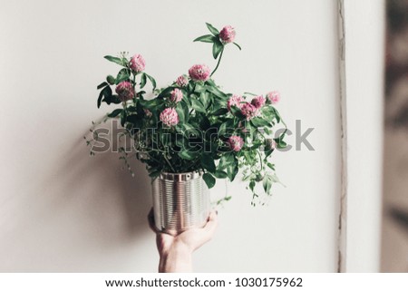 hand holding clover bouquet with pink flowers in metallic cane. wildflowers in rustic rural home. country slow living