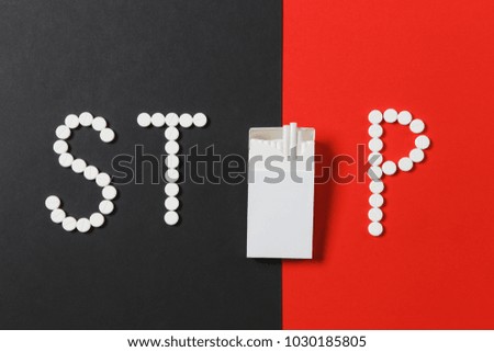 Medication white round tablets in word Stop. Creative composition with message Stop smoke cigarettes on red black background. Concept of health, choice, healthy lifestyle. Copy space advertisement