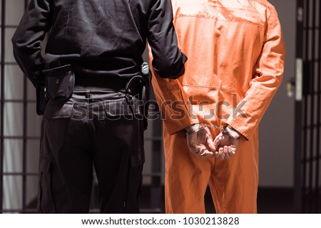 rear view of prison officer leading prisoner in handcuffs Royalty-Free Stock Photo #1030213828