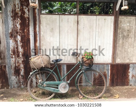A vintage bicycle with old zinc rusty wall and retro bicycle with flower basket in front of