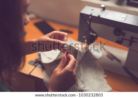 Young seamstress making some repairs, manually sewing