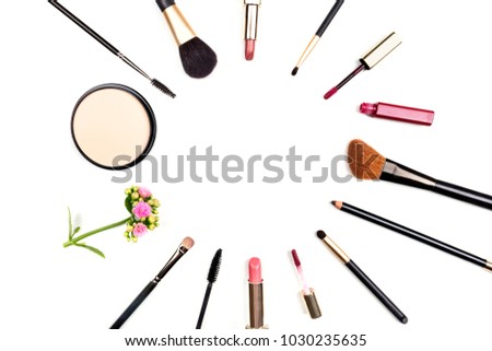 Makeup brushes, pencil, lipstick, other accessories, and a flower, forming a frame on a white background, with copy space. A template for a makeup artist's business card or flyer design