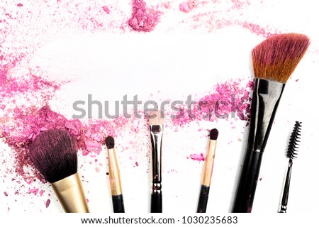 Traces of vibrant pink powder and blush forming a frame, with makeup brushes and a place for text. A template for a makeup artist's business card or flyer design, with copy space
