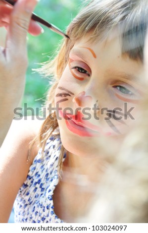 outdoor portrait of a child with his face being painted
