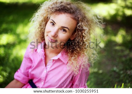 Portrait of beautiful  girl with curly hair in the summer park

