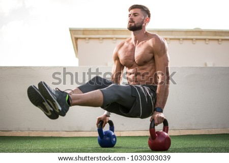 Muscular shirtless man workout with kettle bells in  L Sit position at rooftop gym. Royalty-Free Stock Photo #1030303039